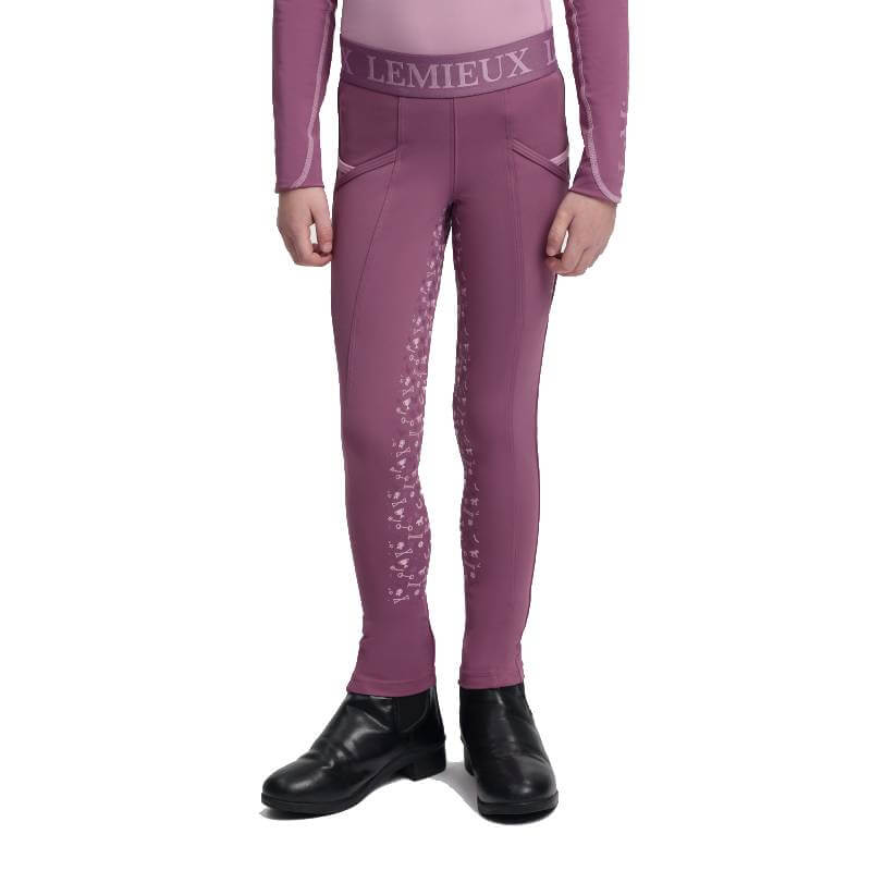 Child wears LeMieux Mini Pull On Breech Mallow, black boots, on white background.