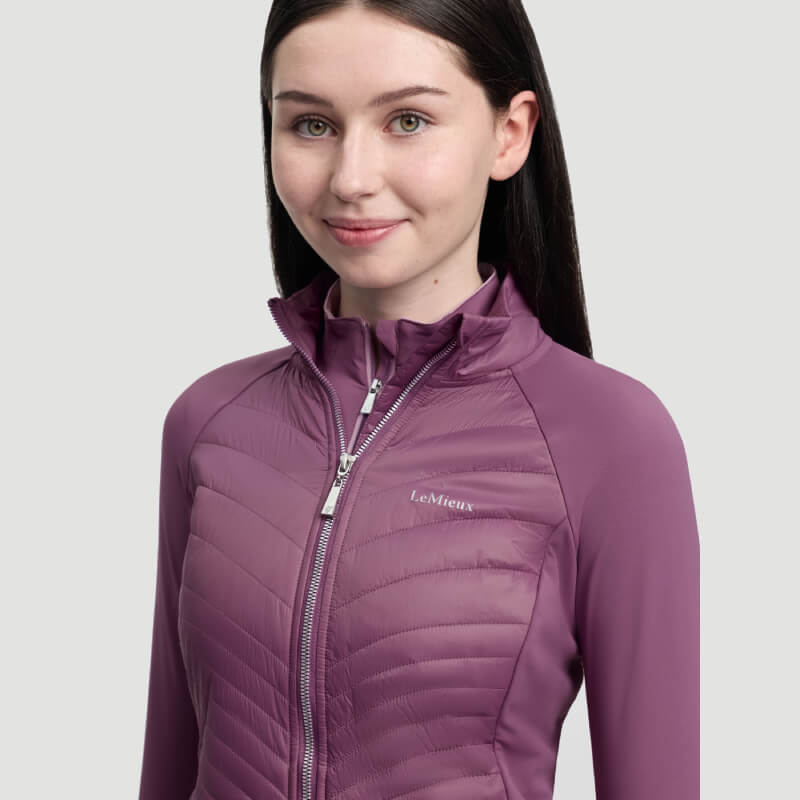 Woman with long dark hair in LeMieux Young Rider Josephine Jacket Mallow, against plain background.