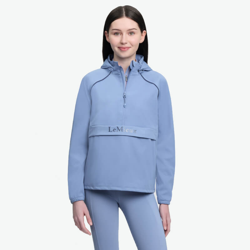 Woman in LeMieux Young Rider Paige Quarter Zip Waterproof Jacket, Powder Blue, smiling.