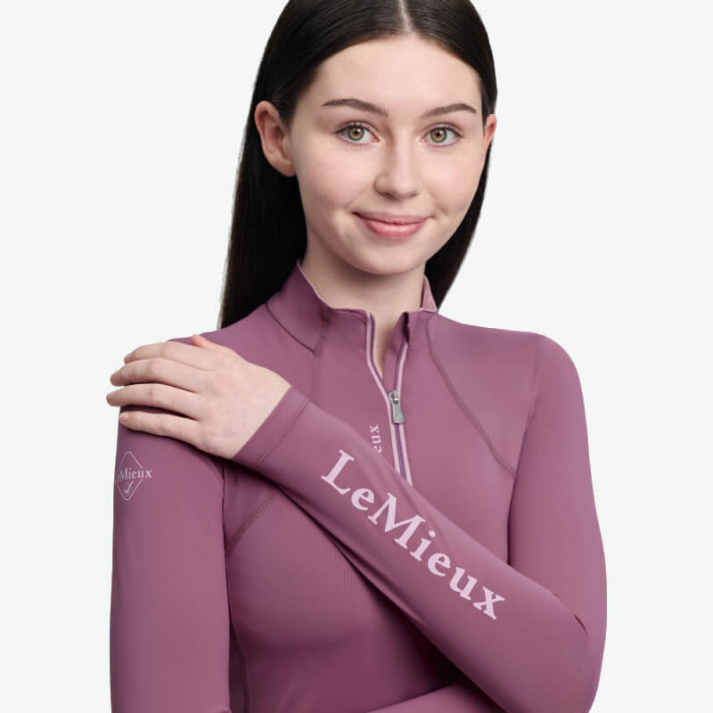 Woman in a LeMieux Young Rider Classique Baselayer Mallow smiles, arms crossed over chest.