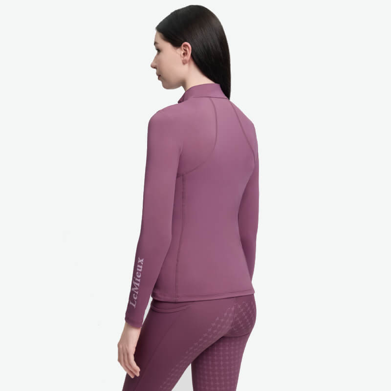 Woman in LeMieux Young Rider Classique Baselayer Mallow, facing away, long dark hair, logo sleeve.