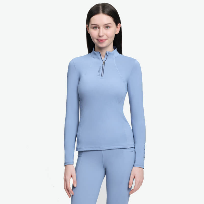 Smiling woman in LeMieux Young Rider Classique Baselayer Powder Blue athletic riding outfit.