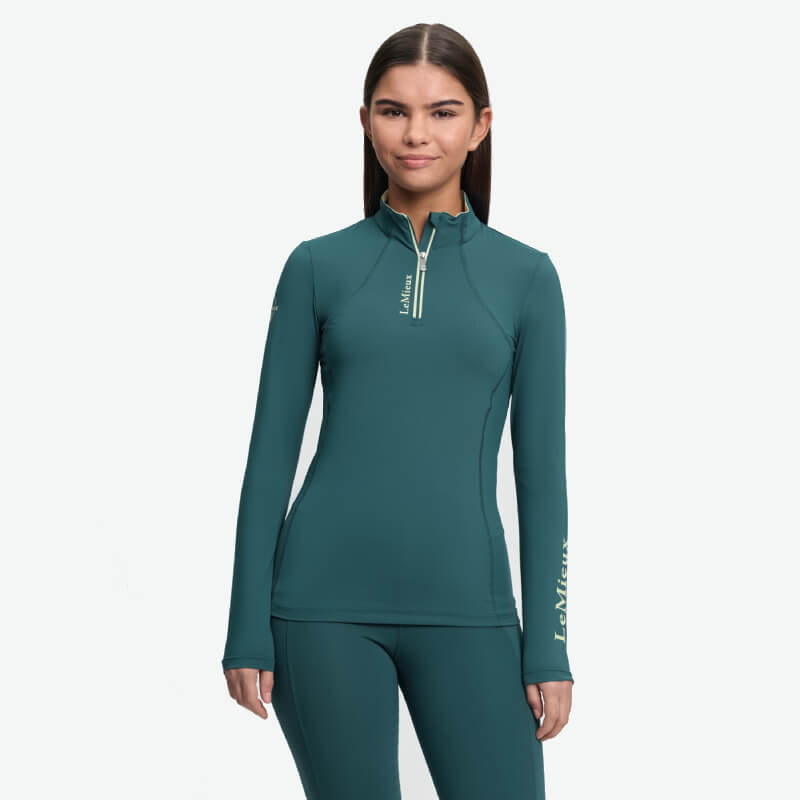 Girl in LeMieux Young Rider Classique Baselayer Jungle, facing forward in zip top and leggings.