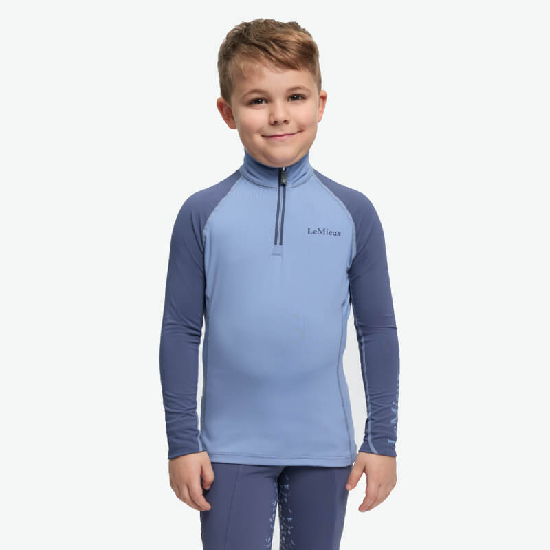 LeMieux Mini Baselayer in Powder Blue, a moisture-wicking kids’ riding top with dark sleeves.