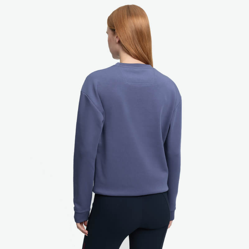Person with long hair wears LeMieux Christina Crew Sweat Shadow and black pants, facing away.