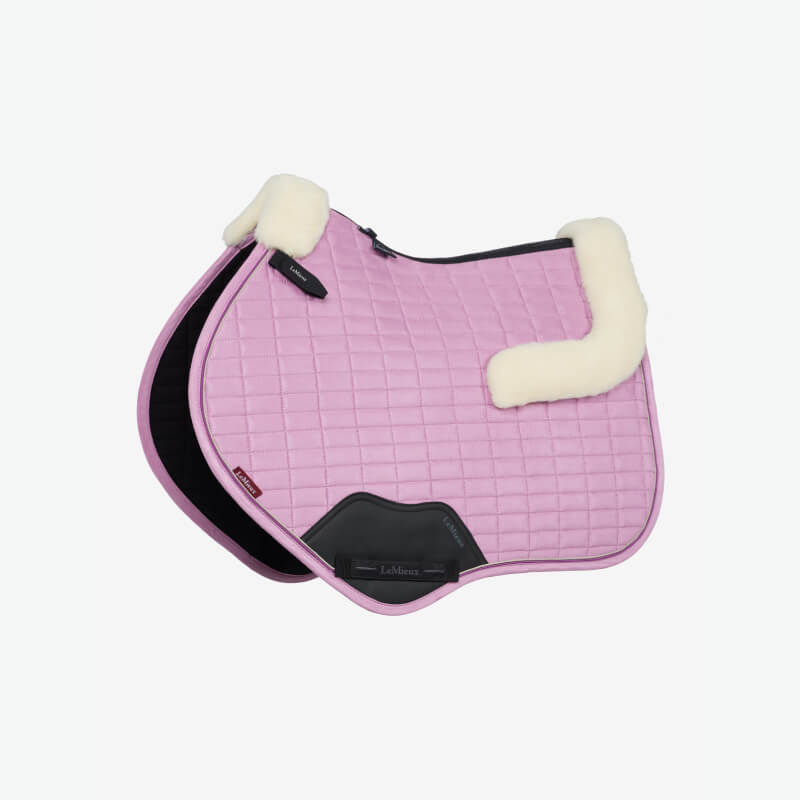 Close-up of a black saddle with a pink LeMieux Merino+ Suede Close Contact Square Fondant pad.