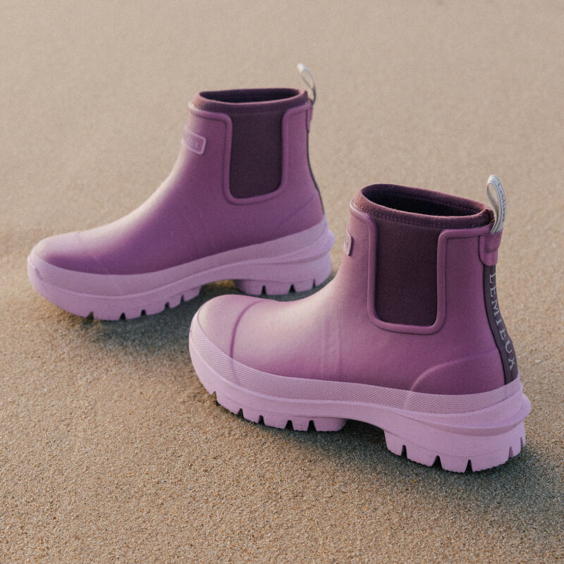 Two LeMieux Bramshaw Chelsea Welly Mallow rest on sand.