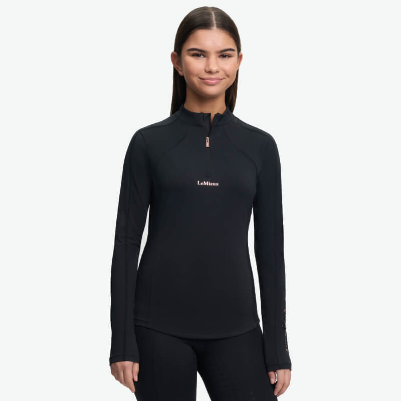 Woman wearing a black LeMieux Young Rider Sparkle Baselayer, standing and smiling.