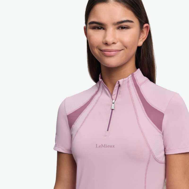 Teen girl in LeMieux Young Rider Mia Mesh Baselayer Fondant, smiling in a light purple top.