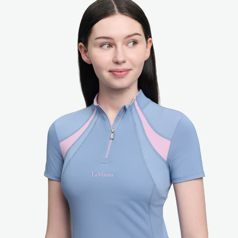 Girl wearing LeMieux Young Rider Mia Mesh Baselayer Powder Blue, looking sideways and smiling.