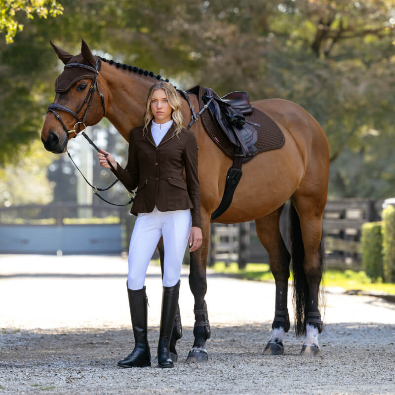 Woman in equestrian attire stands by a brown horse wearing the LeMieux Brilliance Close Contact Square Espresso.