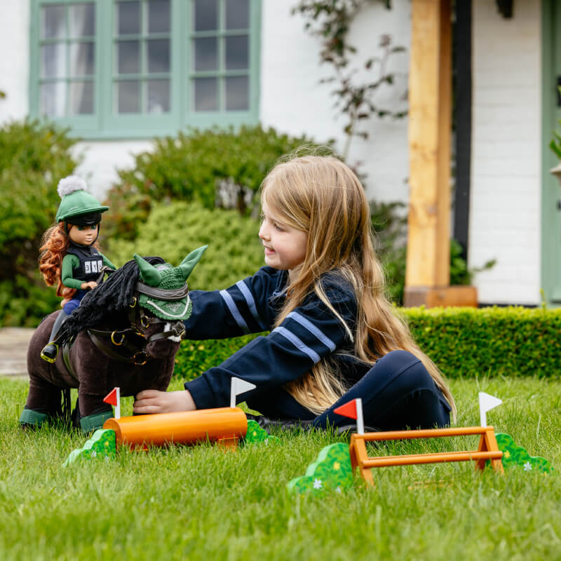 Young girl plays outside with the LeMieux Toy Pony XC Jump Set Multi.