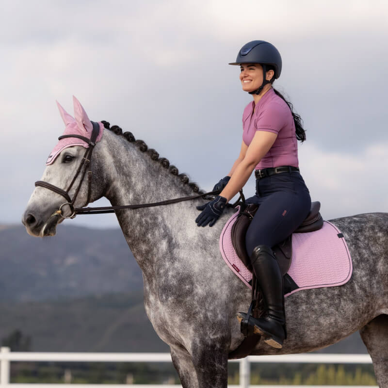 Smiling rider in pink on gray horse, using LeMieux Essence Close Contact Square Fondant.