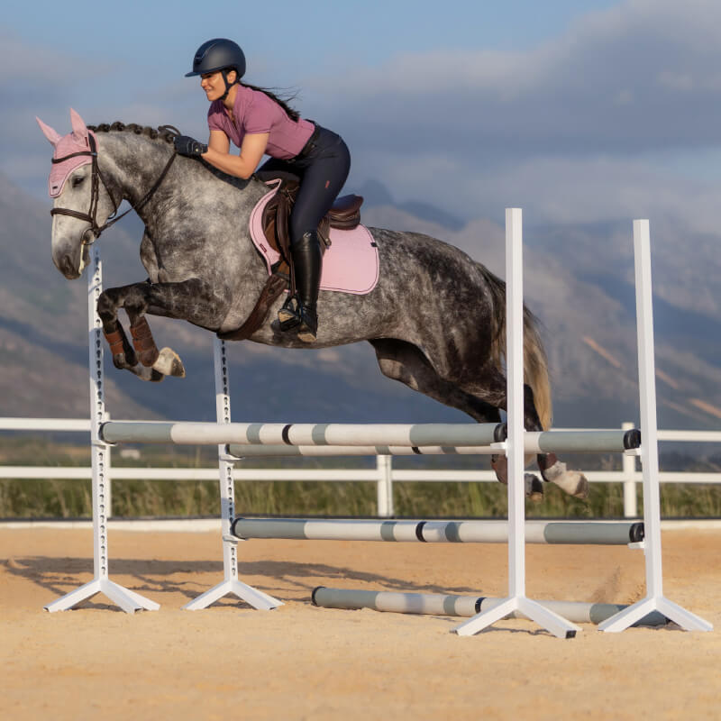 Rider on gray horse mid-jump with LeMieux Essence Close Contact Square Fondant saddle pad.