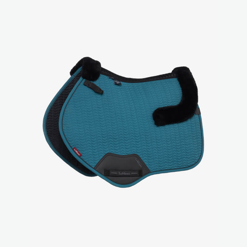 Brown leather saddle on LeMieux Merino+ Essence Close Contact Square Jungle with green foliage.