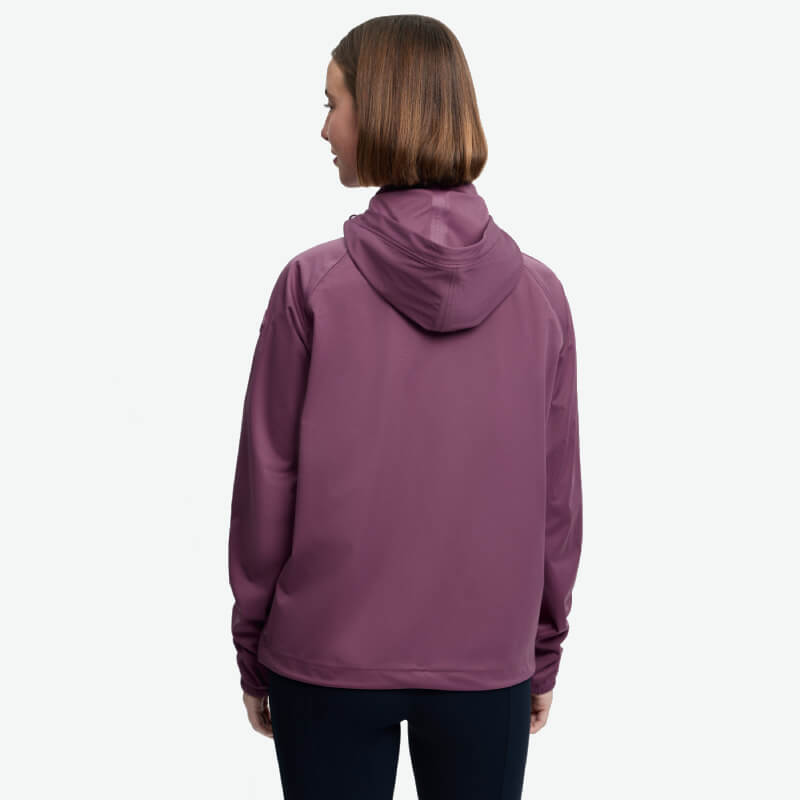 Woman in LeMieux Perri Mallow waterproof hoodie, facing away, on a plain white background.