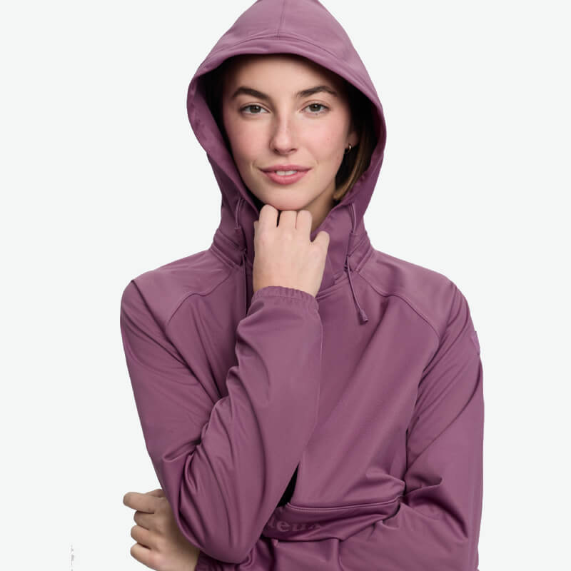 Smiling in a LeMieux Perri Half Zip Waterproof Hoodie in mallow, holding the hood.