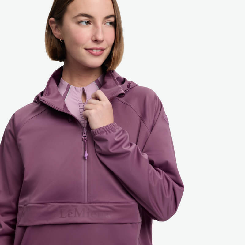Woman in LeMieux Perri Half Zip Waterproof Hoodie Mallow holds the zipper near her collar.