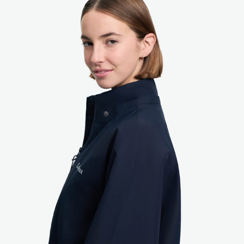 Person with short brown hair in a LeMieux Indra Waterproof Jacket Navy, facing sideways and smiling.