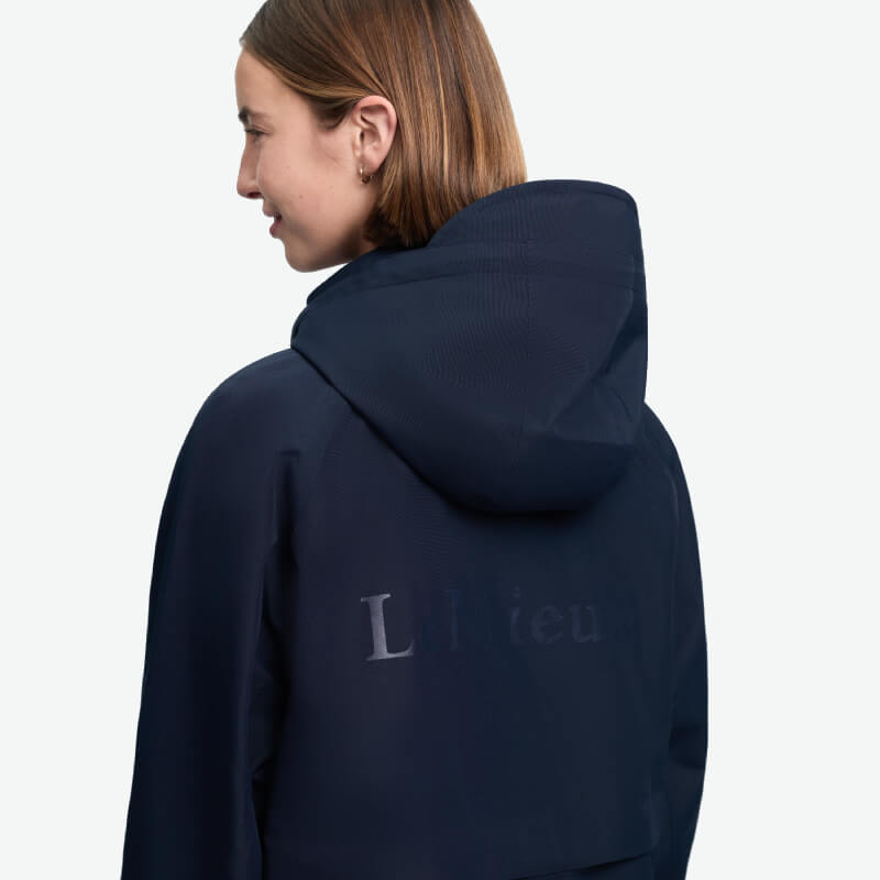 Woman in LeMieux Indra Waterproof Jacket Navy, sideways, with short brown hair.