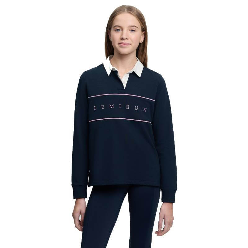Girl wears LeMieux Young Rider Riley Rugby Shirt Navy, standing against a white background.