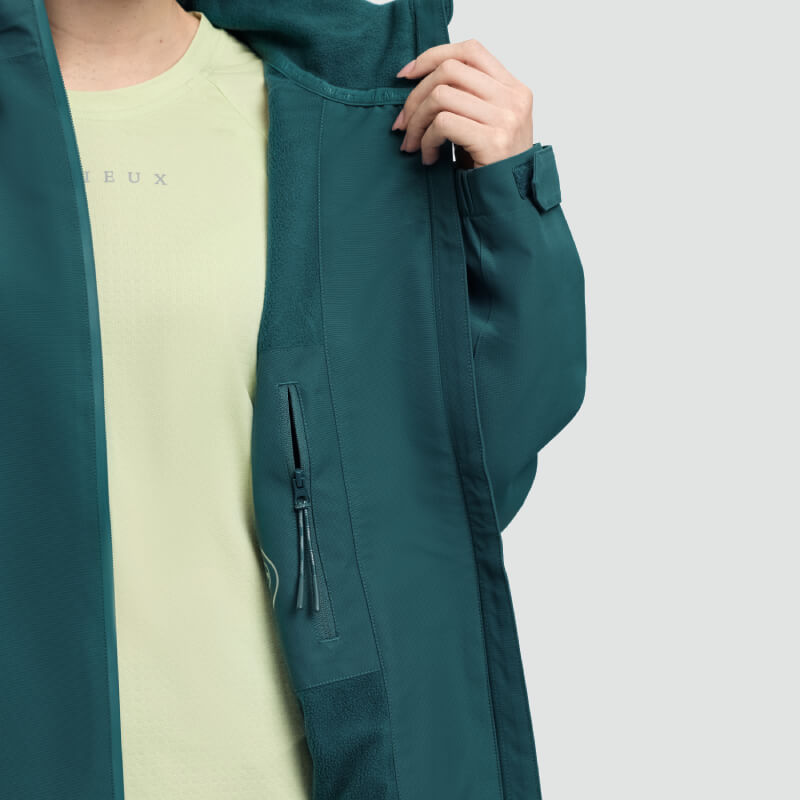 Person in a green LeMieux Indra Waterproof Jacket Jungle shows zippered inner pocket and shirt.