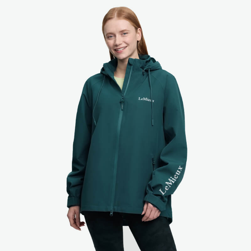 Woman in a LeMieux Indra Waterproof Jacket Jungle, smiling against a plain white background.