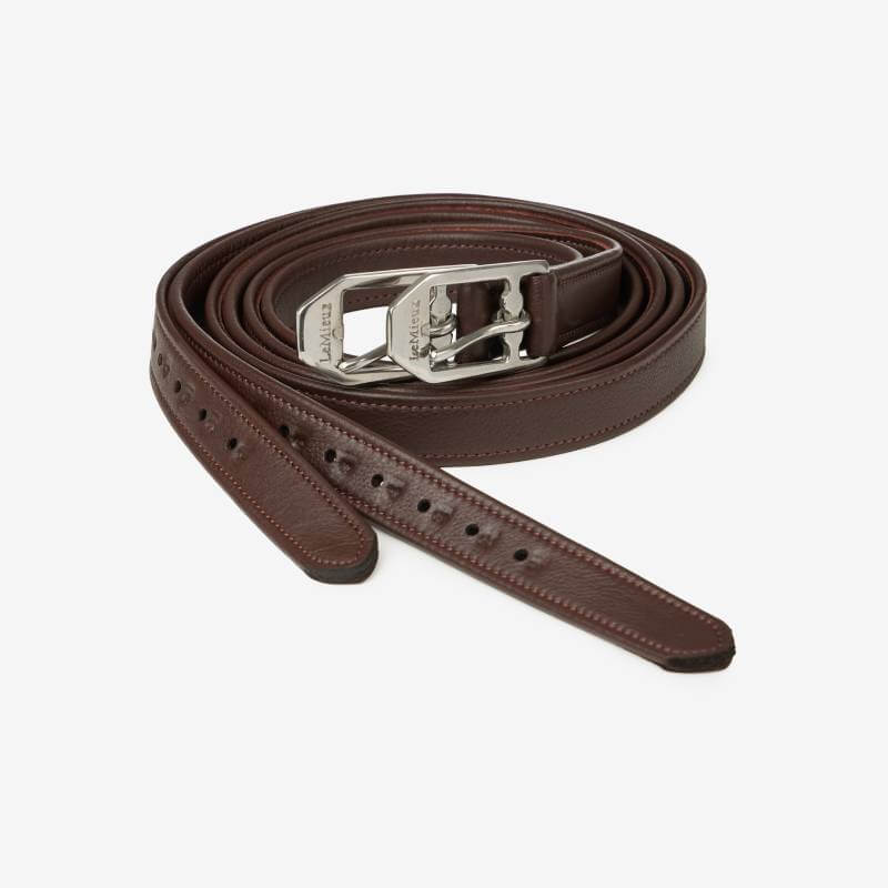 A coiled LeMieux Arika Stirrup Leather Havana belt with a silver buckle on white background.