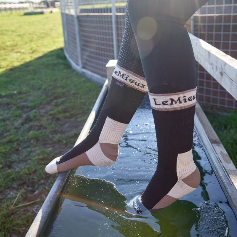 Wearing LeMieux x Sealskinz Waterproof Socks Black, person stands in shallow water trough.