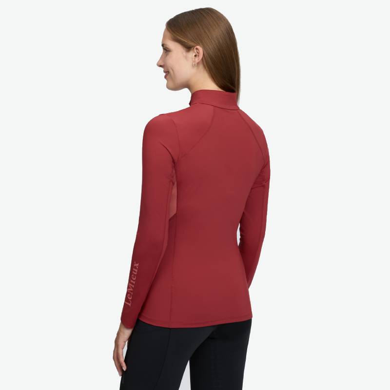 Woman in a red LeMieux Classique Baselayer Russet, back view, hands at her sides.