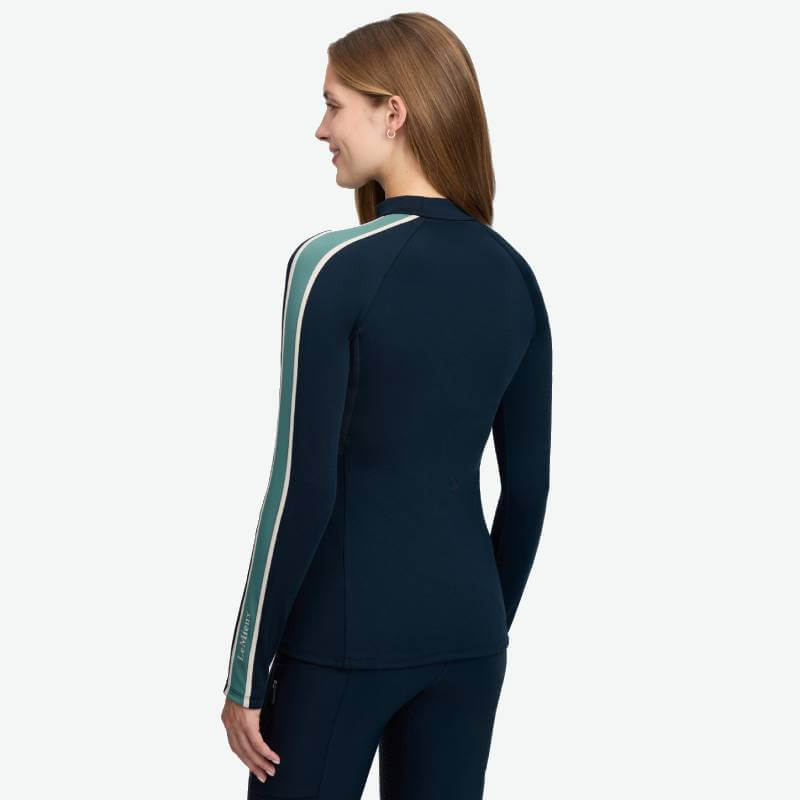 Woman in LeMieux Talia Turtle Neck Baselayer Navy with teal and white striped sleeves.