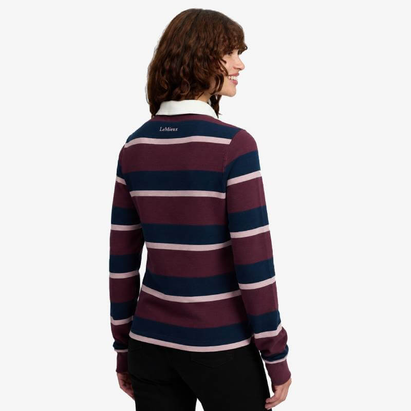Woman in LeMieux Sloane Stripe Rugby Shirt Bramble, maroon/navy/pink stripes, back view.