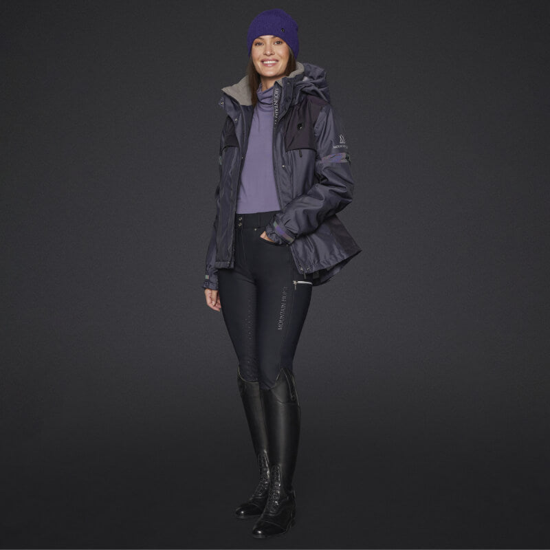 Woman in Mountain Horse Royal Grace Jacket Deep Purple, purple beanie, breeches, tall boots.
