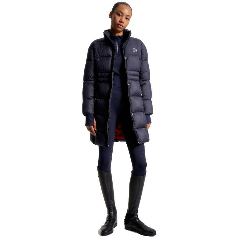 Woman in a Tommy Hilfiger Long Coach Jacket Desert Sky, navy pants, and knee-high black boots.