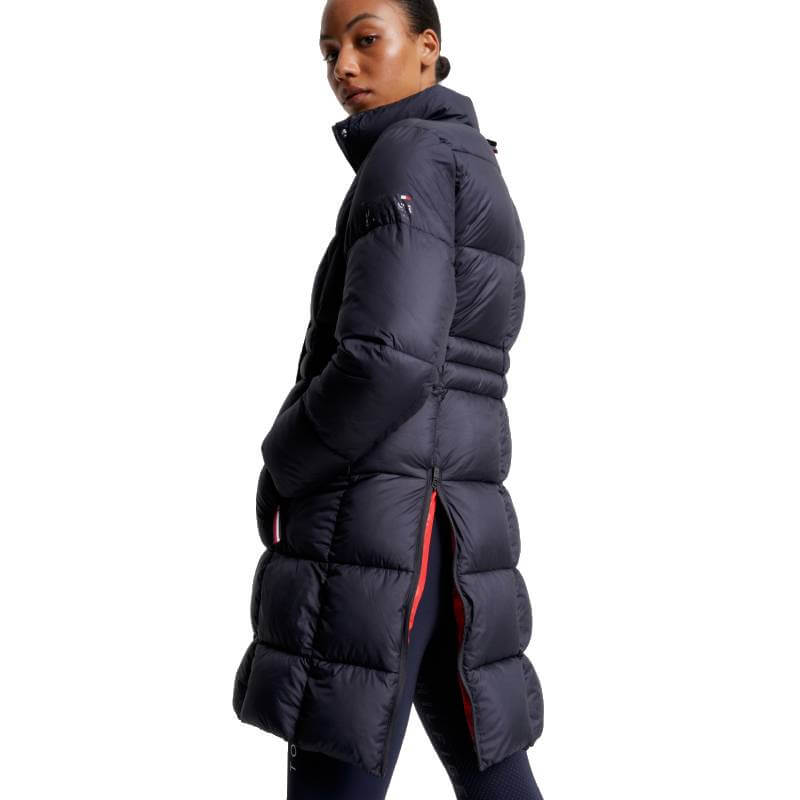 Woman in a Tommy Hilfiger Long Coach Jacket Desert Sky, black leggings, and tall black boots.