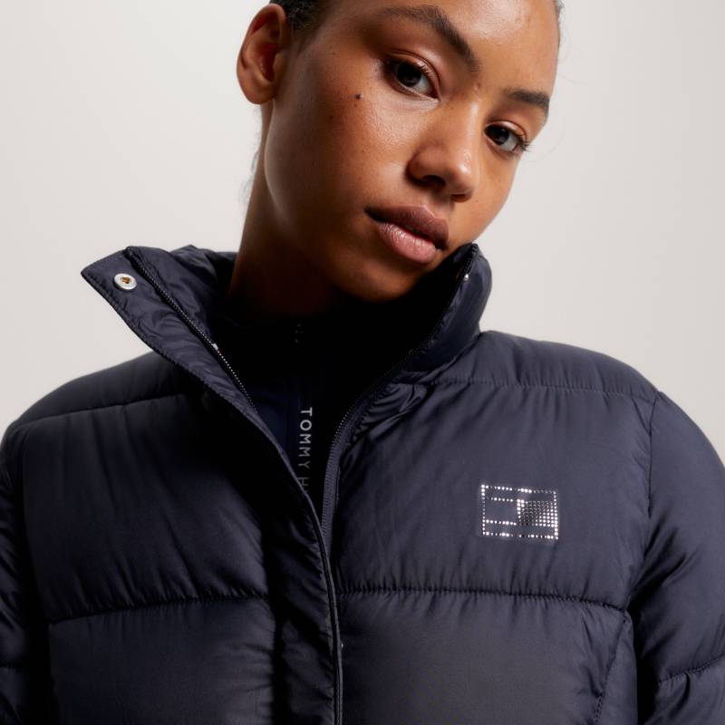 Woman in a Tommy Hilfiger Long Coach Jacket Desert Sky, with logo on chest, facing camera.