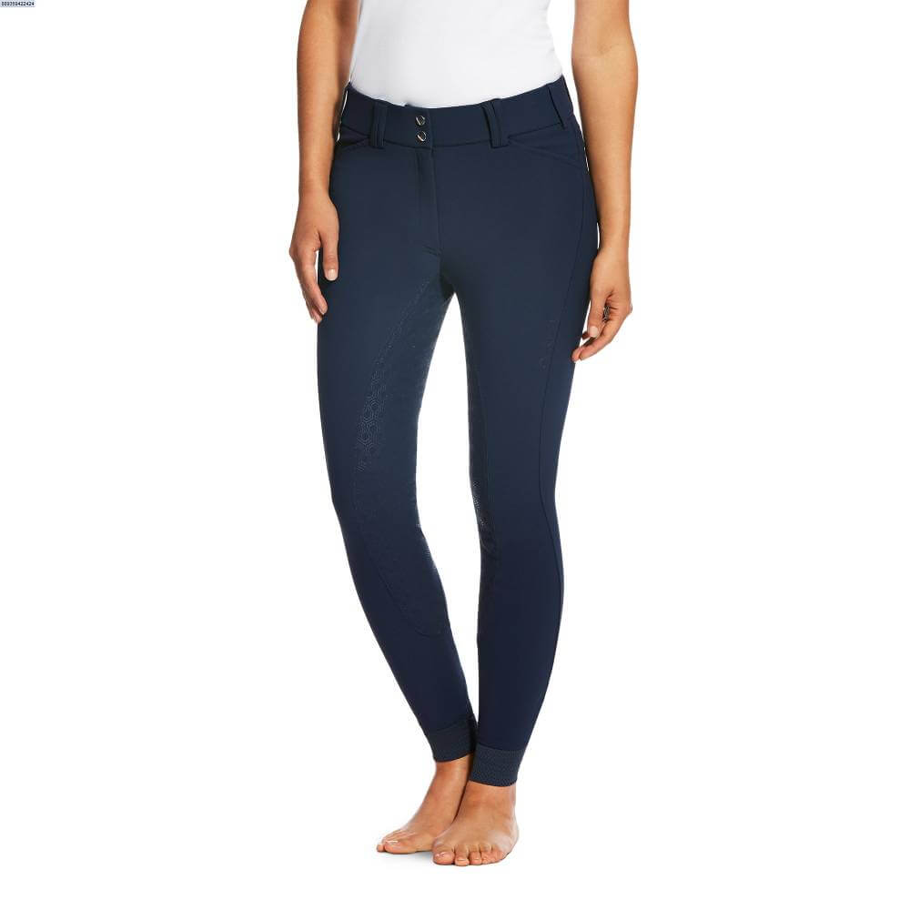 Person wears Ariat Tri Factor Grip Full Seat Navy breech and white top, barefoot against white background.