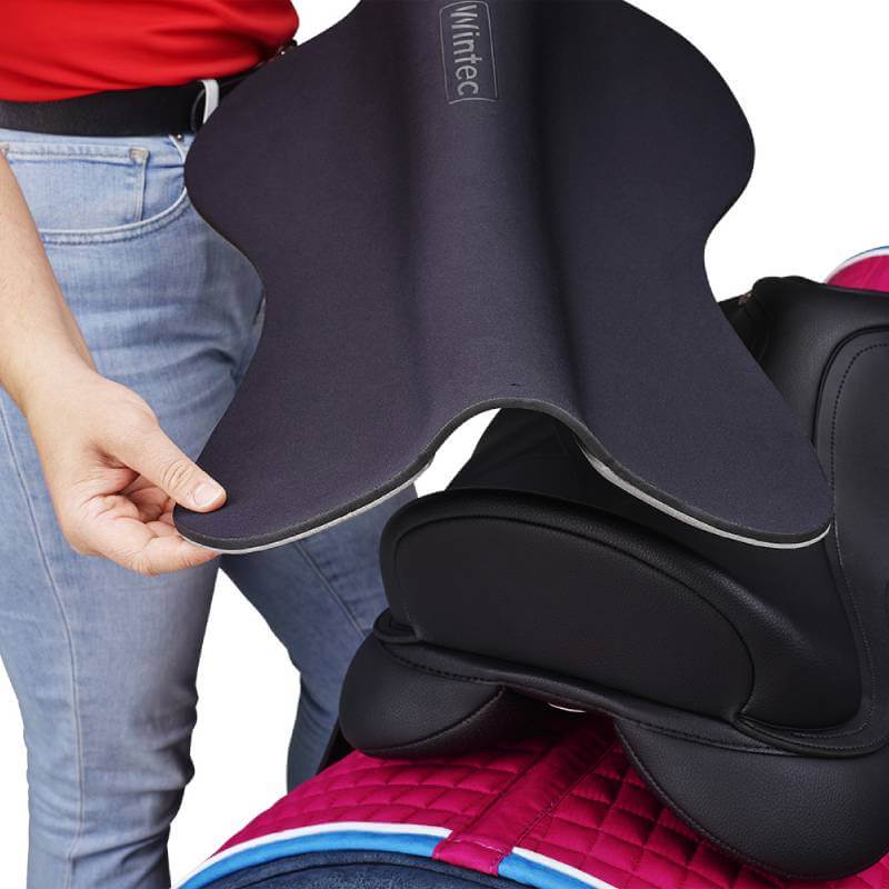 Person placing a Wintec Riser Comfort Pad All Purpose Black on a black saddle with pink pad underneath.