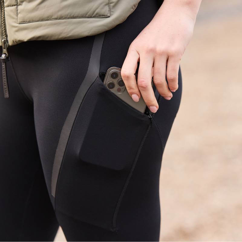 Person sliding a phone into the side pocket of Weatherbeeta Toulon Lifestyle Tights Black.