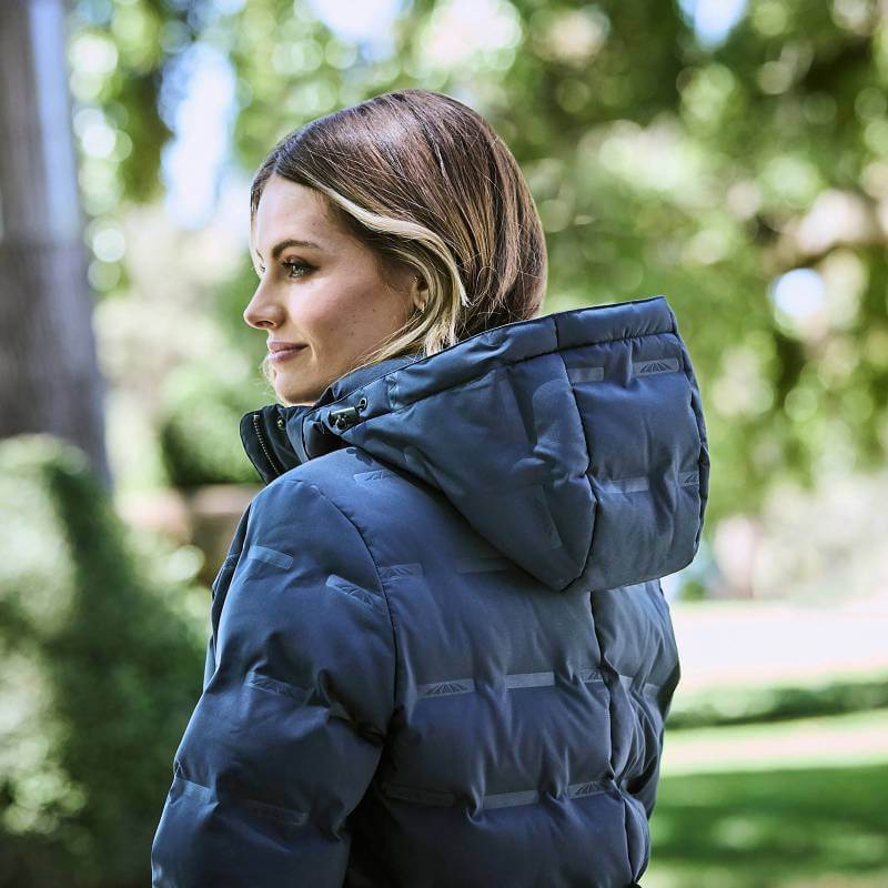 Woman outdoors in Weatherbeeta Helsinki Heat Seal Quilted Jacket Navy Iris, greenery behind.