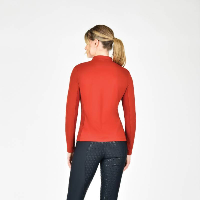 Woman wearing Weatherbeeta Reno Long Sleeve Riding Top Red Ochre, facing away, white background.