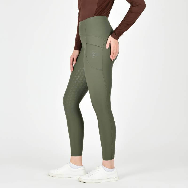 Person in Weatherbeeta Thermal Riding Tights Olive Night, brown top, and white sneakers, sideways.