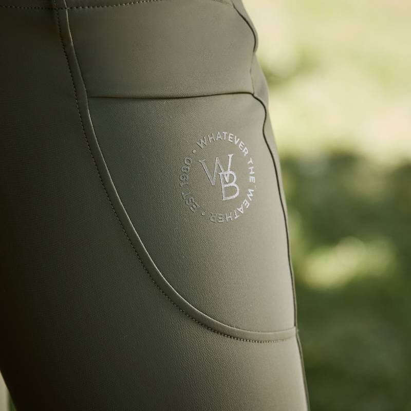 Close-up of olive Weatherbeeta Thermal Riding Tights with WB logo and full seat gel grip pocket.