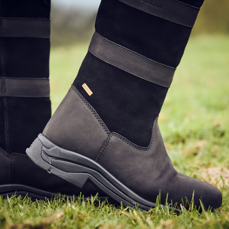 Close-up of Dublin River Boots IV Black by Dublin on grass, highlighting stitching and soles.