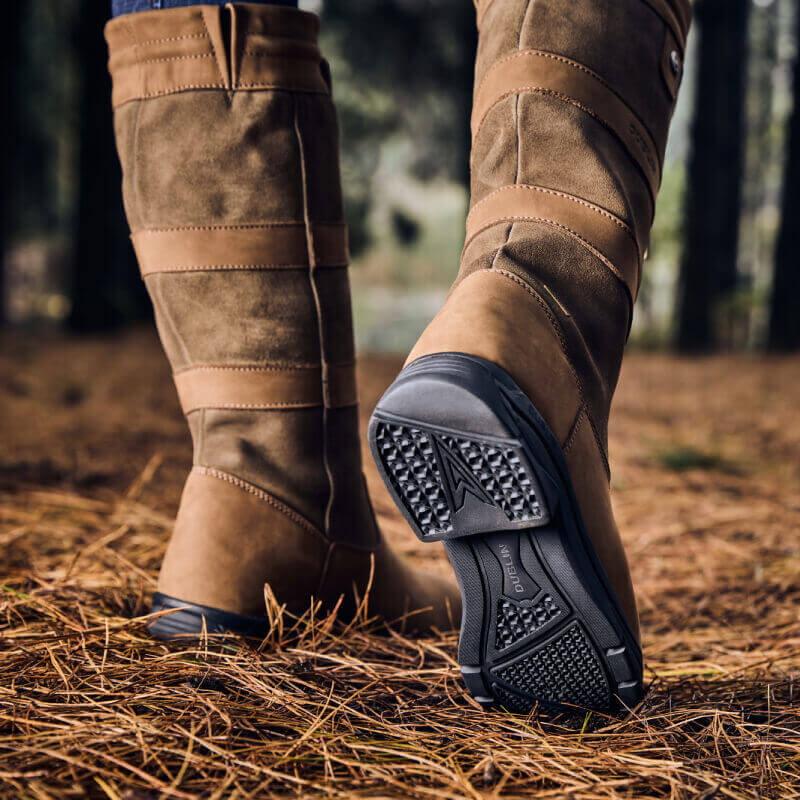 Wearing Dublin River Boots IV Dark Brown, someone walks on pine needles in a forest.