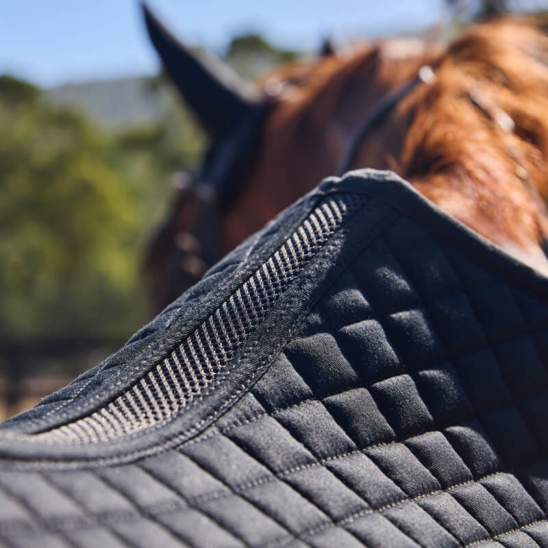 Black Weatherbeeta Prime Air-Tec jump shaped saddle pad with quilted design and logo patch.