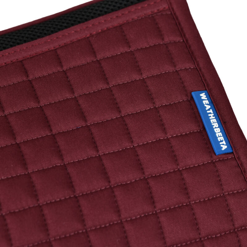 Close-up of a Weatherbeeta Prime Air-Tec Jump Saddle Pad in burgundy with blue label.