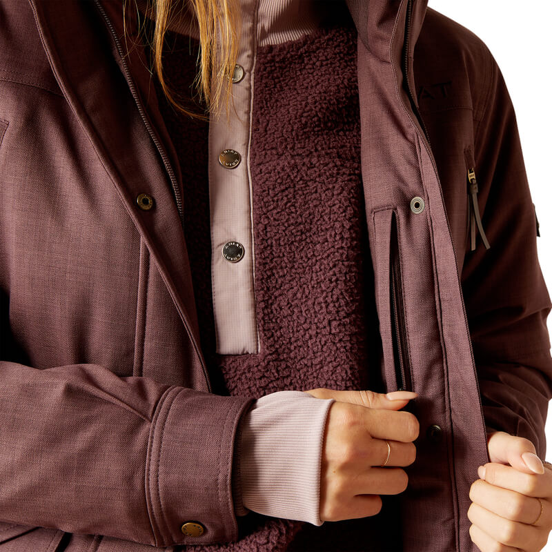 Woman in an Ariat Sterling Insulated H2O Parka Raisin unzips a pocket to reveal fleece pullover.