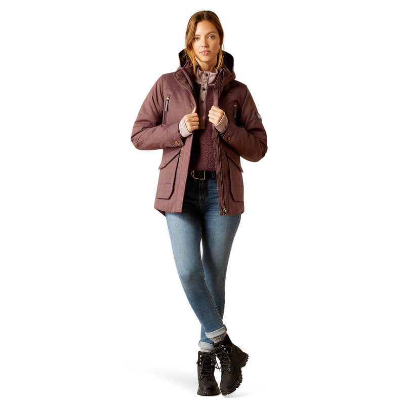 Woman wearing Ariat Womens Sterling Insulated H2O Parka Raisin, jeans, and boots, white background.