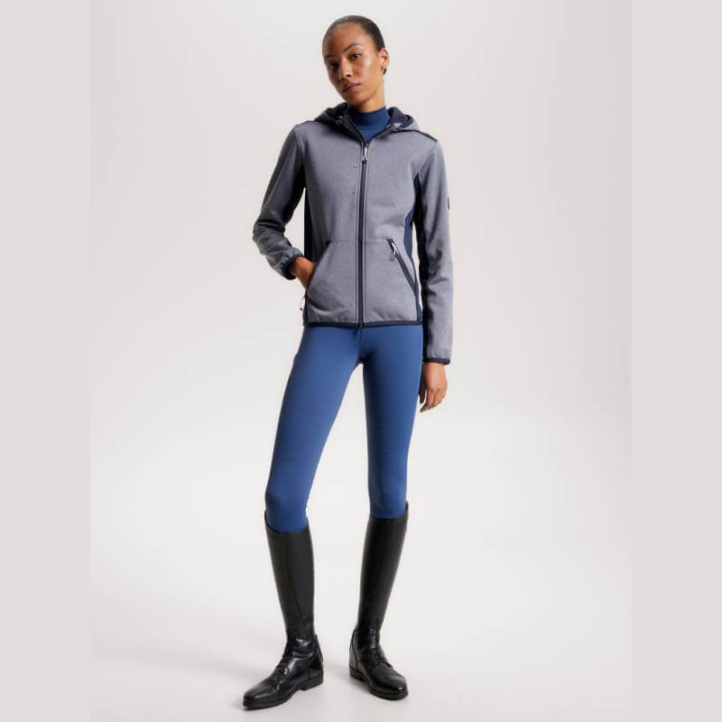 Woman in a Tommy Hilfiger London Softshell Jacket Grey Melange, blue leggings, and black boots.